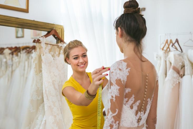 Tailor taking measurements on the wedding dress
