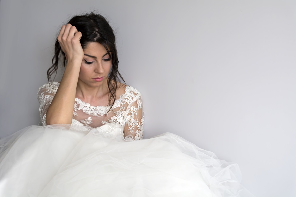 A bride contemplating her wedding dress choice with a professional seamstress ready to offer solutions.